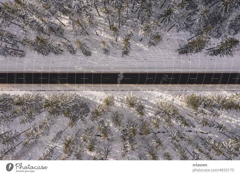 Drohnenaufnahme einer Straße in idyllischer Winterlandschaft bei Sonnenuntergang. Straße läuft durch die Natur aus der Vogelperspektive Wald Dröhnen Antenne