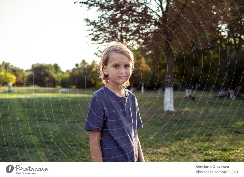 Teenager Junge schaut auf Kamera im Freien Nahaufnahme Lifestyle-Porträt im Park in der Natur. Grünes Gras backgrund Goldene Stunde Sonne Licht Gesicht jung