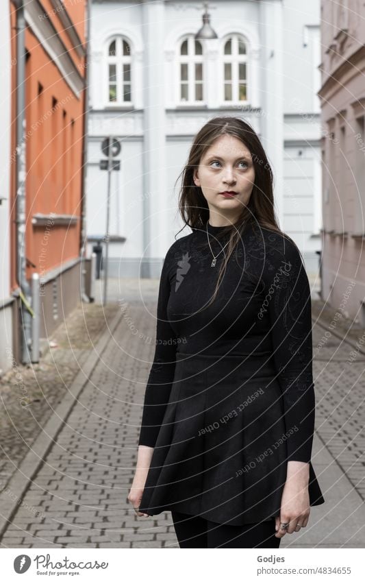 Junge Frau steht in einer Gasse und blickt nach oben Portrait feminin Mensch Gesicht Außenaufnahme Porträt langhaarig authentisch Erwachsene Farbfoto