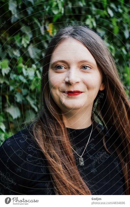 Portrait einer jungen Frau mit langen Haaren und schwarzer Kleidung vor grünem Efeu portrait frau feminin langhaarig blick weiblich Gesicht schön rothaarig