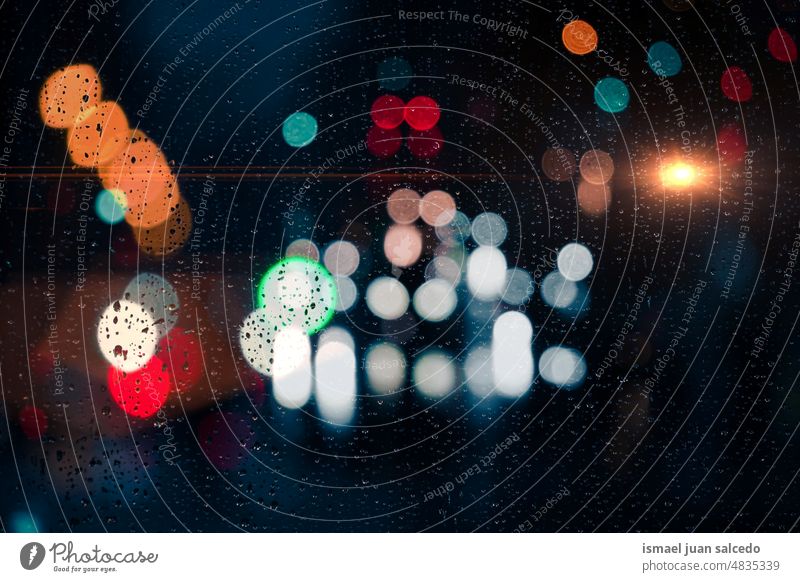 Tropfen auf dem Fenster und Straßenlaternen im Hintergrund bei Nacht Lichter Farben farbenfroh mehrfarbig Bokeh Kreise Regentropfen regnerisch Wasser Glas hell