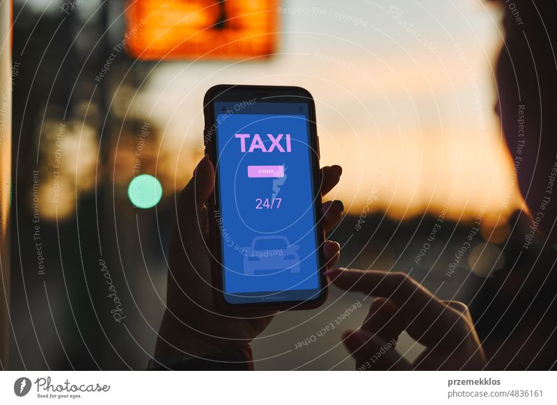 Frau, die ein Taxi online über eine mobile Anwendung auf einem Smartphone bestellt. Taxibestellung über eine Online-Anwendung. Bestellung einer Taxifahrt in einer Straße im Stadtzentrum. Carsharing. Taxidienst auf dem Handy