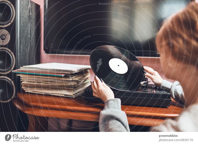 Junge Frau hört Musik von einem Schallplattenspieler. Retro und Vintage-Musik-Stil. Mädchen hält analoge Schallplatte Album. Frau genießt Musik aus alter Plattensammlung