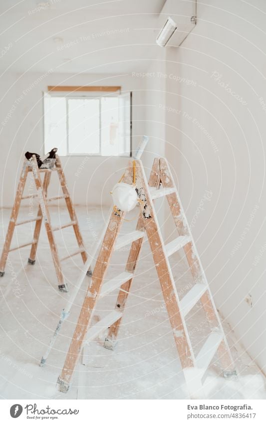 Leitern auf weißem Raum auf der Baustelle. Wände streichen. Heimwerken, Renovierung Werk heimwärts Laufmasche Haus Farben Innenbereich Rolle grau Malerei neu