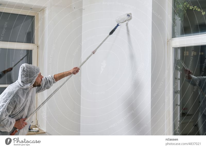 Maler bei der Arbeit mit einem Farbroller, um die Wand eines Zimmers zu streichen. do it yourself concept image Arme abschließen Farbe Konzept Konstruktion