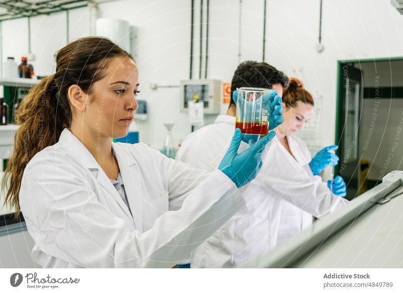 Seriöser Chemiker, der eine Flüssigkeit in einem Kolben im Labor untersucht Frau Wissenschaftler Flasche liquide untersuchen wissenschaftlich Chemikalie