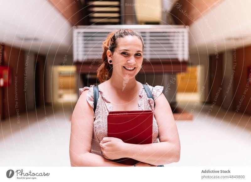 Fröhliche Frau mit Notizbuch in der Universität Schüler Notebook Notizblock schulisch Bildung lernen intelligent gelehrt Planer positiv Hochschule froh Saal