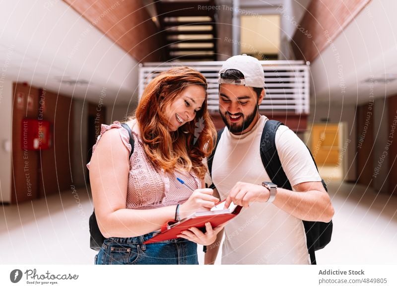 Lächelnde Schüler schreiben in ein Notizbuch Freund zur Kenntnis nehmen Notebook Universität Aufgabe schulisch Bildung lernen intelligent gelehrt Planer positiv