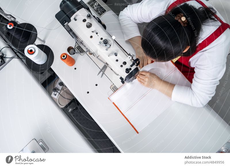 Gesichtslose Näherin an der Nähmaschine in einer Fabrik Damenschneiderin Textil nähen Werkstatt Herstellung Industrie Inszenierung Arbeit Instrument Vorrat