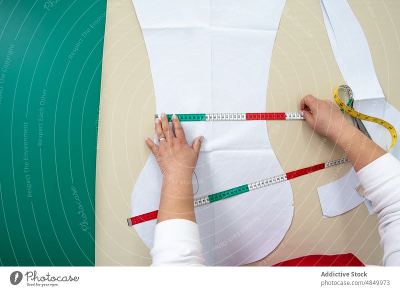 Gesichtslose Näherin misst Papiermuster in der Werkstatt aus Damenschneiderin messen Klebeband Muster Textil Herstellung Industrie Atelier Instrument Vorrat