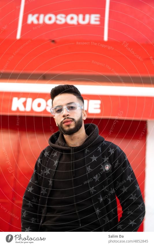 Stilvolle Nahaufnahme eines jungen hübschen Mannes gestylt Styler Stile stylisch schicke Kleidung stilvoller Hintergrund rot Brille Blick Blick in die Kamera