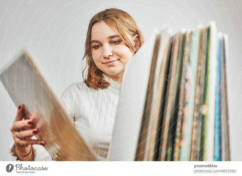 Abspielen von Vinyl-Schallplatten. Hören von Musik aus Vinyl-Schallplattenspieler. Retro- und Vintage-Musikstil. Junge Frau sucht analoge LP-Album in Stapel von alten Platten