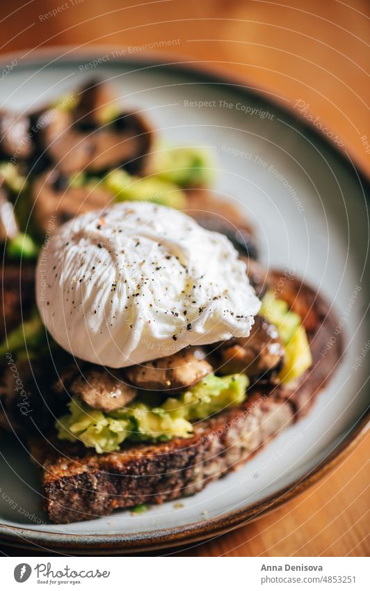 Gesundes Frühstück aus pochierten Eiern und Pilzen Zuprosten pochiertes Ei Avocado Sauerteigbrot Vegetarier Gesundheit Lebensmittel Eigelb Belegtes Brot