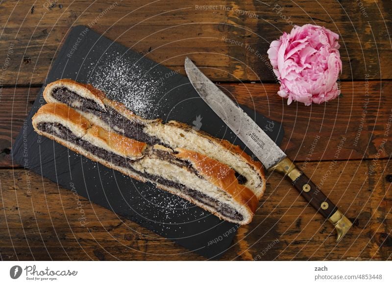 Geschmacksexplosionen Kuchen Backwaren Foodfotografie backen Lebensmittel Puderzucker süß lecker Blüte Blume Mohn Mohnkuchen Mohnstrudel Messer