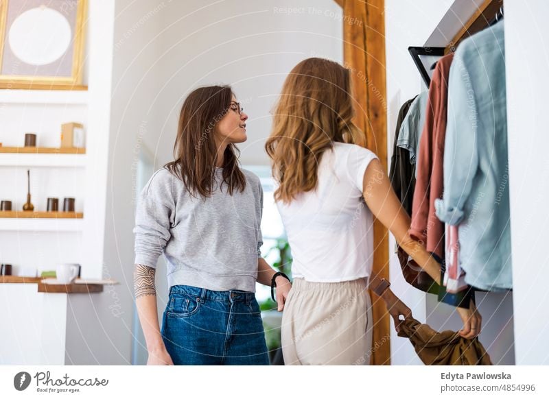 Zwei junge Frauen, die zu Hause ihre Kleider aus dem Kleiderschrank aussuchen gleichgeschlechtliches Paar Erwachsener Appartement attraktiv schön Bonden