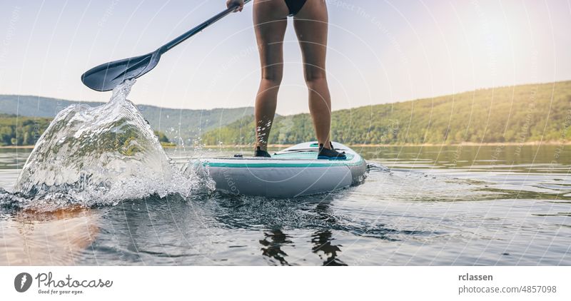 Sportliches Mädchen beim Stand Up Paddle Surfen Paddel Holzplatte stehen nach oben See Paddelbrett Wasser Abenteuer SUP Frau Wassersport Brandung Erholung