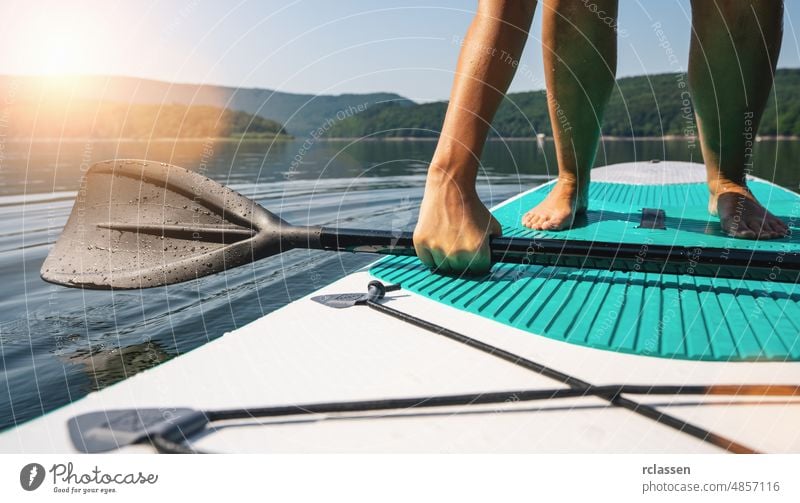 Person auf Paddelbrett versucht aufzustehen Holzplatte nach oben See Sport Wasser Abenteuer SUP Frau Wassersport Brandung Erholung reisen Spaß Aktivität