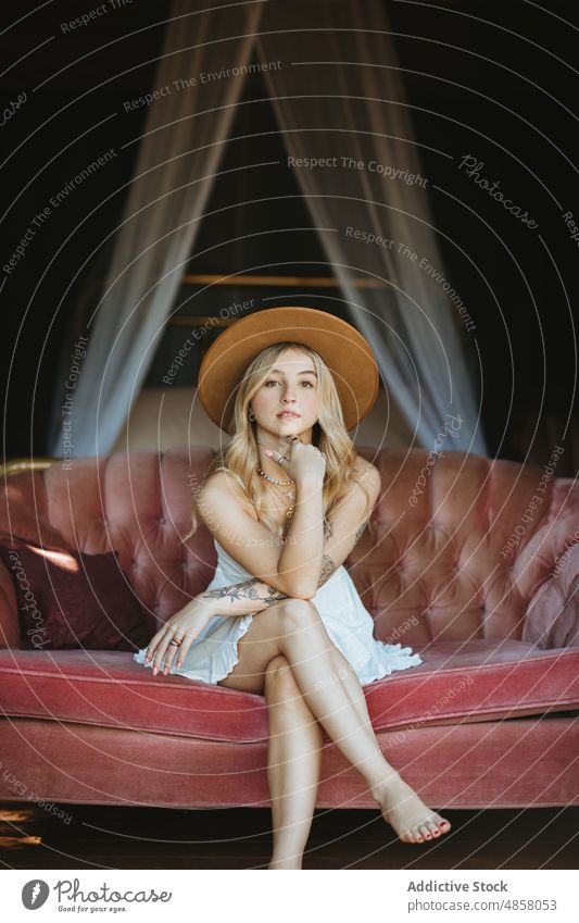 Frau mit Hut sitzt im Innenhof patio Terrasse Stil Vorschein feminin ruhen Hinterhof Mode Sommer Gebäude charmant räkeln Kopfbedeckung Dame Sommerzeit Sofa