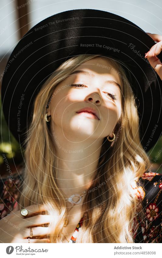 Frau mit Hut auf Terrasse Vorschein feminin Stil Sonnenlicht patio Mode verträumt Stilrichtung Sommer charmant trendy Kopfbedeckung Sonnenschein attraktiv Dame