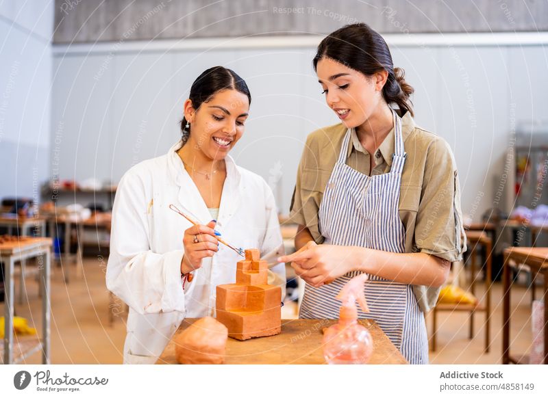 Fröhliche hispanische Frauen arbeiten gemeinsam mit Ton Kunstgewerbler Töpferwaren Zusammensein kreieren Geometrie Form Freundin Lächeln Kleinunternehmen jung