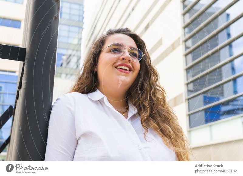 Lächelnde Frau mit Blazer auf der Straße Gebäude Großstadt Vorschein Stil urban Mode Outfit feminin Haus froh heiter Wand Konstruktion Stadt Sommer Dame trendy