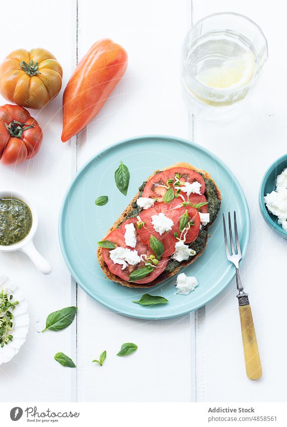 Caprese-Toast auf Holztisch serviert Zuprosten Tomaten Brot lecker Pesto-Sauce Erdöl Salatbeilage Snack Belegtes Brot Gemüse Mozzarella Käse frisches Basilikum