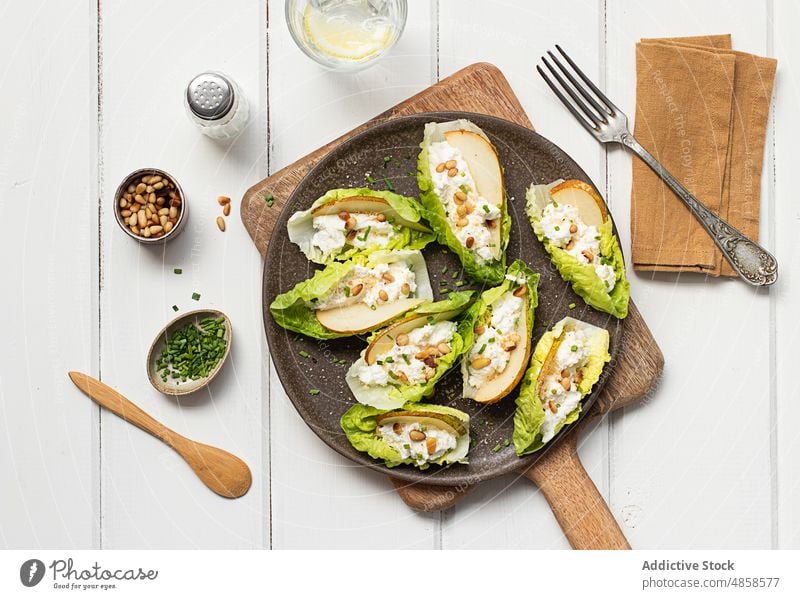 Birnen-Ricotta-Salat mit Kopfsalat auf Holztisch Hintergrund geschmackvoll natürlich Scheiben Gemüse Ritzel Samen Käse Mahlzeit Abendessen Bestandteil grün