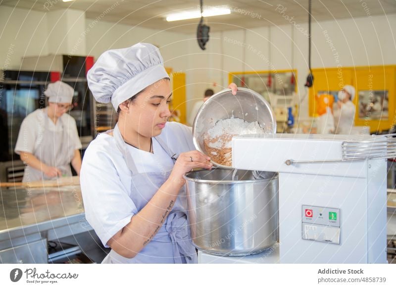 Frau, die eine Zutat in den Mixer gibt Bäcker Bestandteil eingießen Maschine Gerät Vorrichtung kulinarisch Bäckerei Schalen & Schüsseln Küche Arbeit Produkt