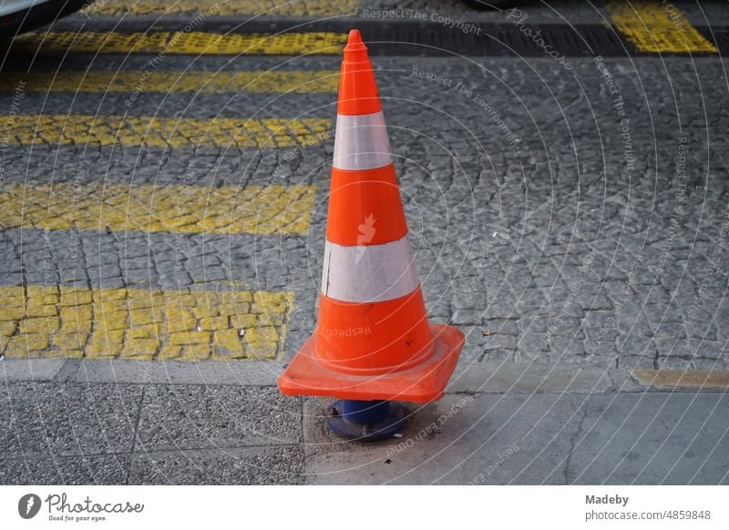 Verkehrsleitkegel oder Pylon aufgesteckt auf einem Polier an einem gelben Zebrastreifen auf altem Kopfsteinpflaster in der Altstadt von Konak im Licht der untergehenden Sonne am Konak Platz im alten Smyrna und heutigen Izmir am Ägäischen Meer in der Türkei