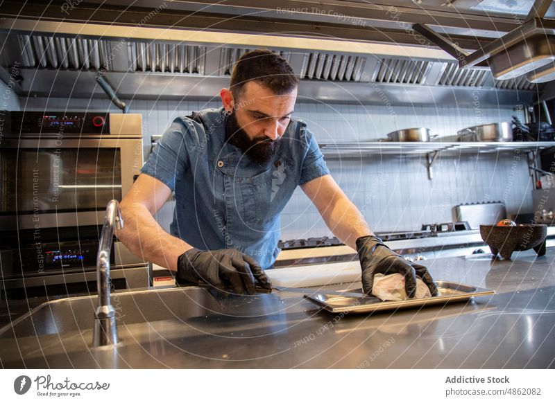 Focused Chef Placing gefülltes Fleisch auf Backblech in der Küche Küchenchef Platzierung Zeug Messer Fokus vorbereitend Lebensmittel Konzentration