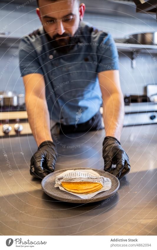 Koch arrangiert Tortillas auf dem Tresen in der Küche Küchenchef arrangierend Teller Abfertigungsschalter Restaurant Essen zubereiten Fladenbrot Lebensmittel