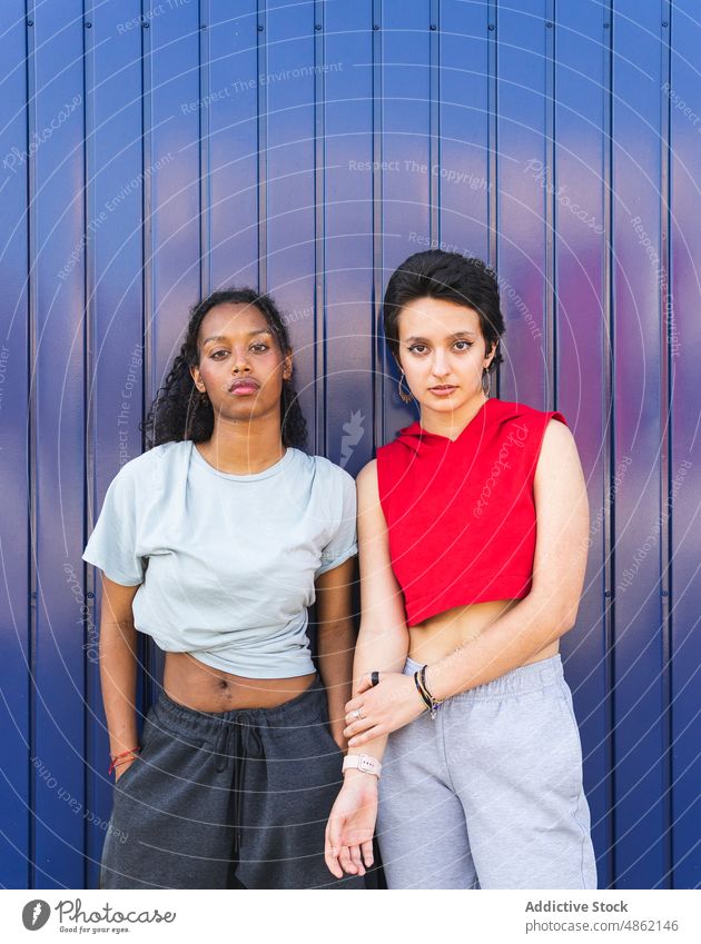 Verschiedene Frauen stehen in der Nähe der blauen Wand Freund lässig Bonden sportlich Straße Großstadt Stil Vorschein Zusammensein Freundin Freundschaft ernst