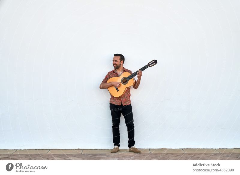 Fröhlicher Mann spielt Akustikgitarre akustisch Musiker Gitarre Lächeln Gitarrenspieler Straße Gesang spielen Hobby Wand Instrument Glück Klang ausführen