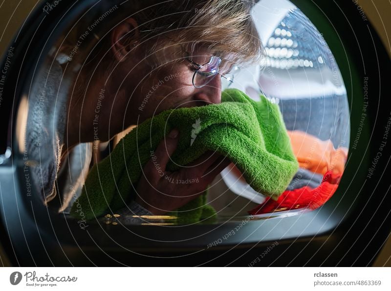 Hausfrauengerüche auf sauberer Wäsche frisch aus der Waschmaschine oder dem Trockner Kleidung Waschsalon heimwärts Wäscherei rot Pflege Brille reif Frau