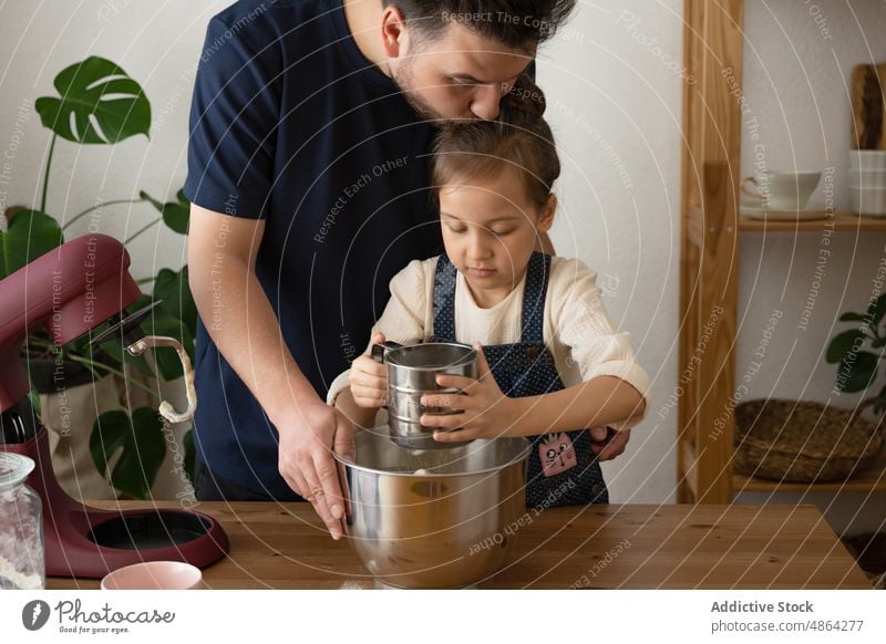 Vater und Tochter sieben Mehl in eine Rührschüssel Sieben Mischen Schalen & Schüsseln heimwärts Liebe Küssen Mixer Teigwaren Tisch Familie Lebensmittel