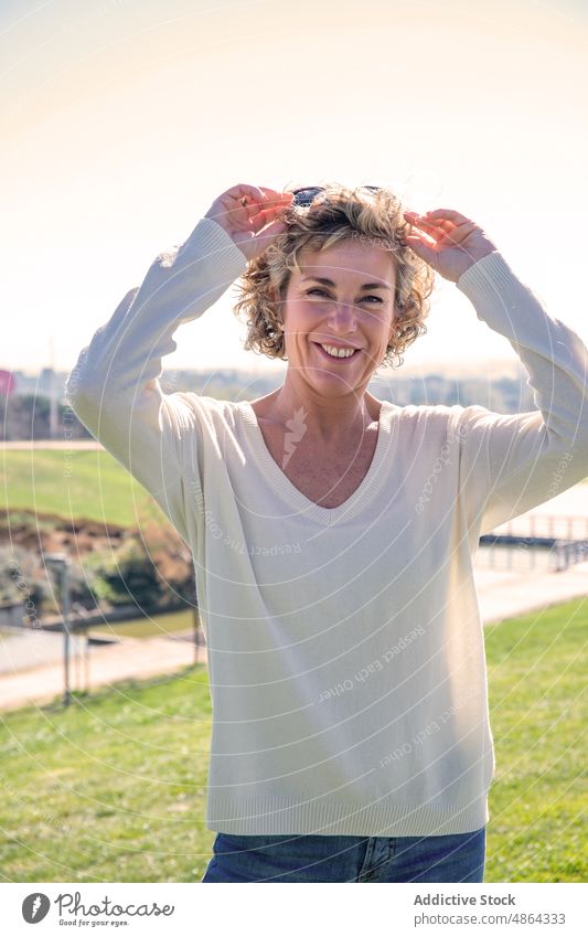 Lächelnde Frau mit Sonnenbrille auf einer Wiese stehend Porträt reif Stehen Sommer lässig Lifestyle Freizeit sonnig Glück Himmel blond Blick Erwachsener schön