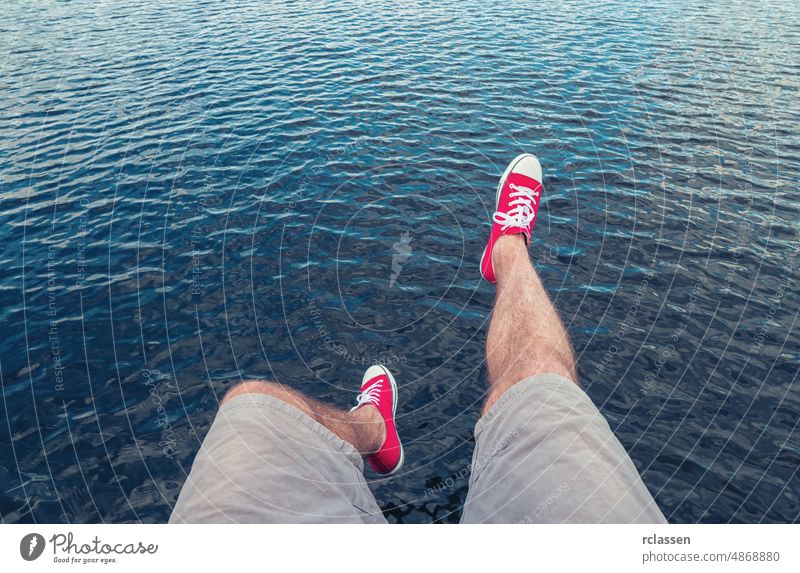 Junger Mann in roten Turnschuhen springt in den Ozean, Point of view shot pov Menschen Lifestyle Punkt Ansicht Sommer Weg Kaukasier Nahaufnahme jung