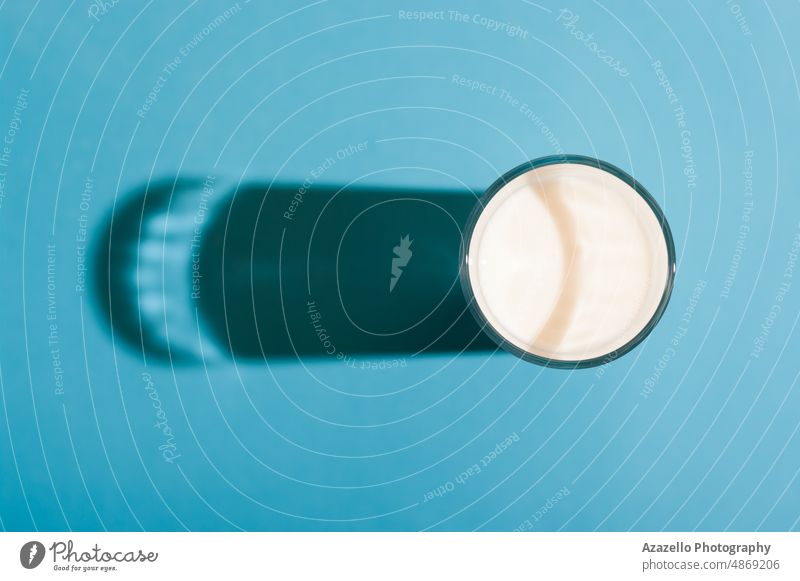 Glas Milch in der Draufsicht mit Schlagschatten auf blauem Hintergrund. melken Pastell Stillleben Minimalismus Schatten trinken Kuh Bauernhof natürlich