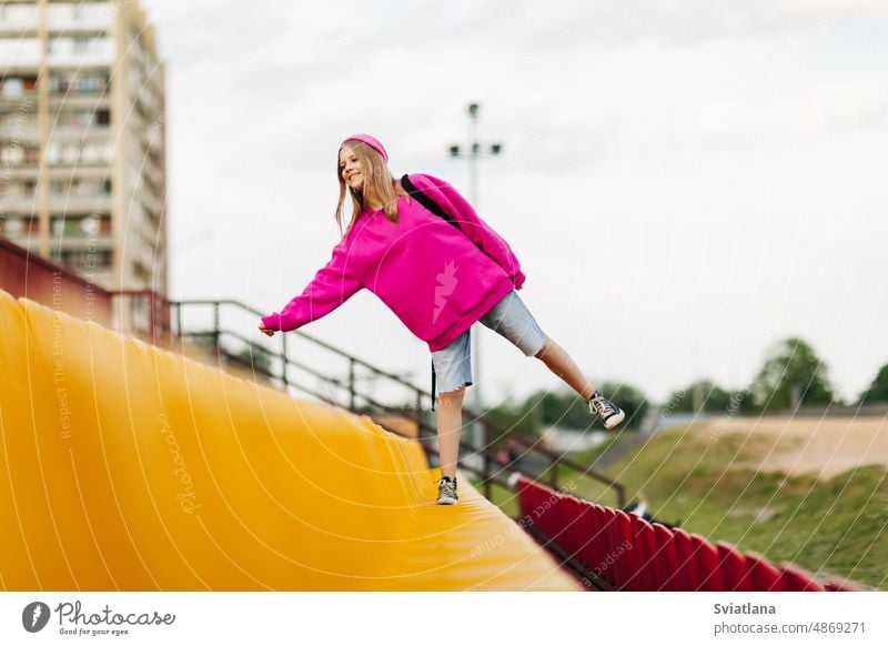 Ein junges Mädchen mit einem Rucksack läuft durch die Tribüne des Schulstadions Schule Schüler Teenager Schulzeit Bildung Frau Porträt Stadion Hintergrund