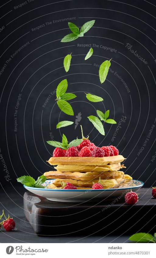 Stapel gebackener belgischer Waffeln mit reifen roten Himbeeren Minze Wafer hölzern Bäckerei Belgier Belgien Beeren Levitation fallen Frühstück braun Knusprig