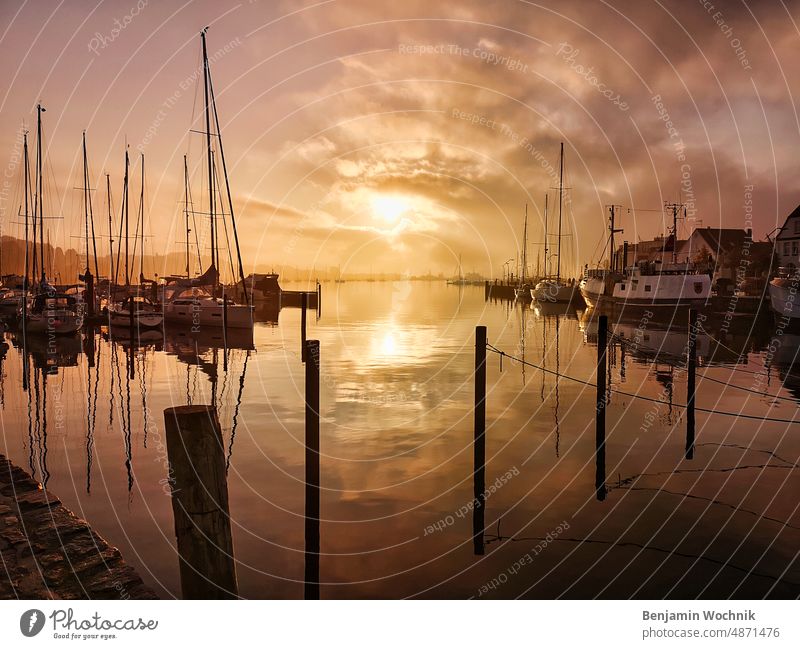 Sonnenaufgang im Hafen von Eckernförde Segelboot windstille Ostsee Kaimauer Seenebel Schiff Boot reede glattes Wasser dramatischer himmel