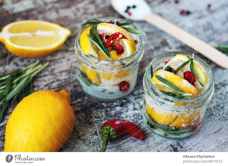 Fermentierte Zitronen in Gläsern mit Salz, Chilipfeffer und Rosmarin. Probiotika Fermentierte Lebensmittel. Eingelegte Zitronen. fermentierte Nahrung nahöstlich