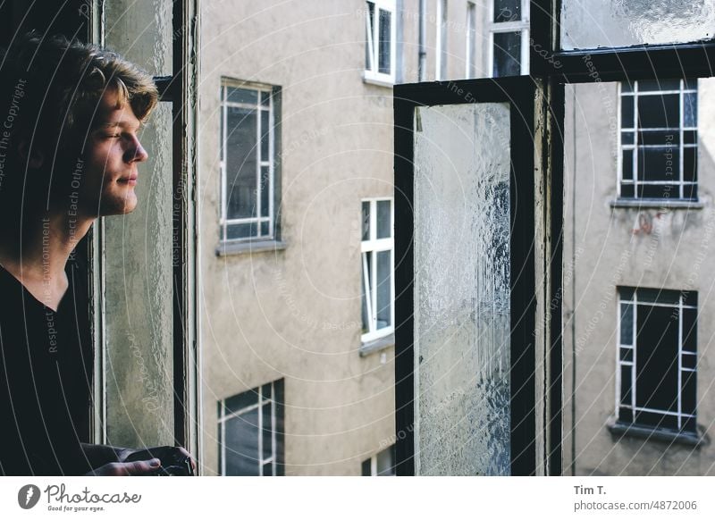 Junger Mann am Treppenhausfenster blond Fenster Prenzlauer Berg Berlin Farbfoto Stadt Stadtzentrum Hauptstadt Tag Altstadt Haus Altbau Architektur Bauwerk Hof