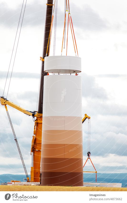 Bau und Montage einer Windkraftanlage per Kran auf einer Baustelle. Ackerland mit Bauarbeiten am Windpark in Deutschland. Energiesparkonzept aus dem Bau von Windkraftanlagen mit Wolkenhimmel