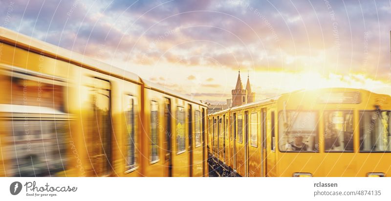 Berliner U-Bahn mit Oberbaumbrücke im Hintergrund im goldenen Abendlicht bei Sonnenuntergang mit dramatischen Wolken, Berlin Friedrichshain-Kreuzberg