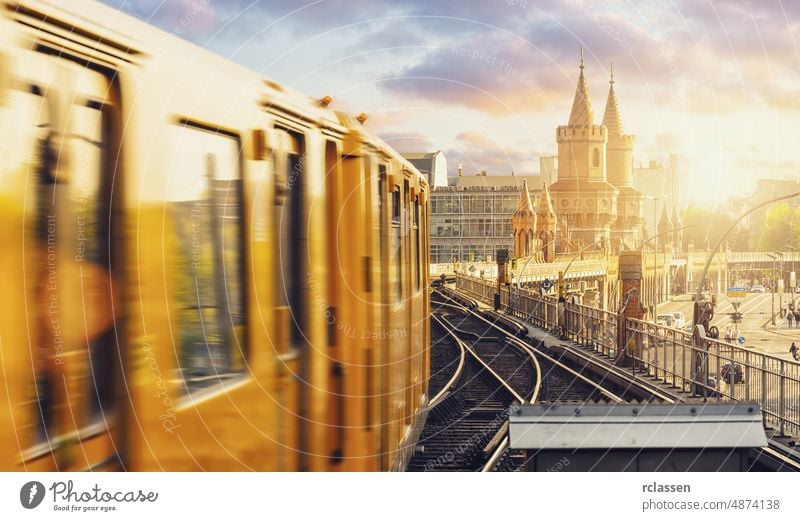 Panoramablick auf die Berliner U-Bahn mit der Oberbaumbrücke im Hintergrund im goldenen Abendlicht bei Sonnenuntergang mit dramatischen Wolken, Berlin Friedrichshain-Kreuzberg