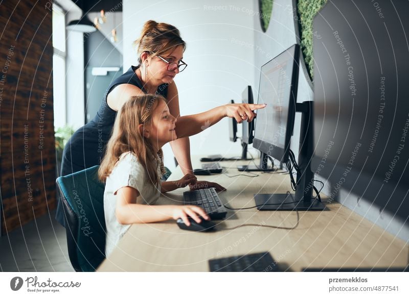 Computerunterricht in der Schule. Lehrer unterstützt Schülerin beim Unterricht in der Grundschule. Kind lernt Computer auf elementaren Informatikunterricht. Zurück zur Schule