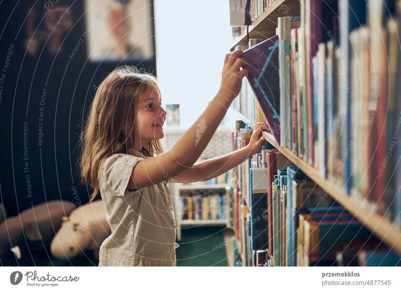 Schulmädchen wählt Buch in Schulbibliothek. Kluges Mädchen wählt Literatur zum Lesen aus. Aus Büchern lernen. Vorteile des täglichen Lesens. Kindliche Neugierde. Zurück zur Schule