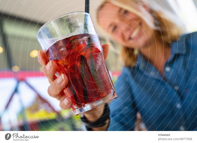 Frau stößt an, sagt Prost und hält tropische Mischfrucht-Margaritas. Getränk aus Wassermelone und Passionsfrucht mit Eiswürfeln in einer Bar. Alkohol Bier blond