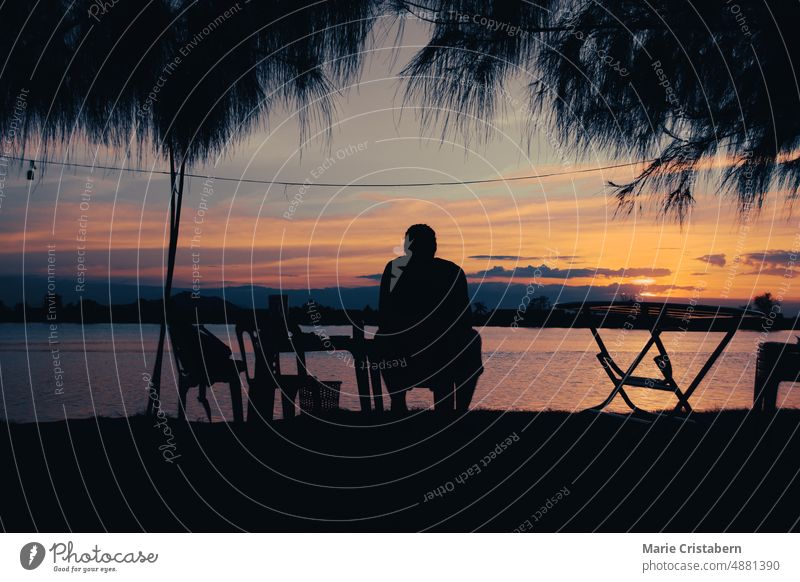 Silhouette eines Mannes, der den Blick auf den Sonnenuntergang am Flussufer in Kampot, Kambodscha, genießt Sonnenuntergangs-Ansicht Freizeit